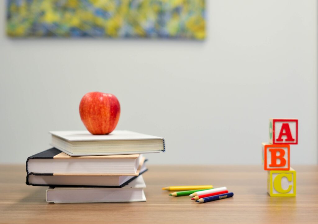 Photo of a school attributes. Apple, books, pens.